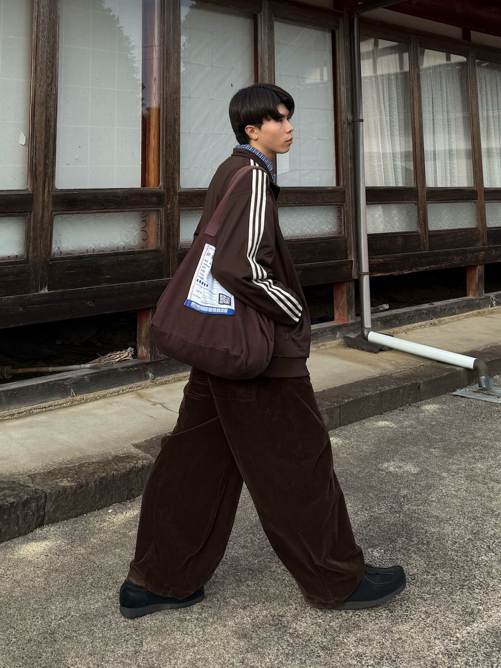ブラウン系のジャージ、ブラウン系のトートバッグ、ブラック系のモカシン/デッキシューズを着用したメンズの秋コーディネートの3枚目の写真