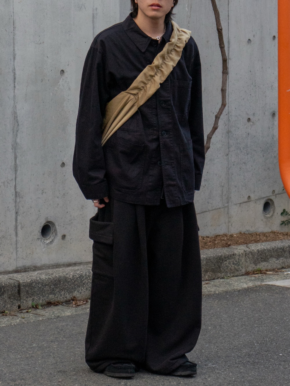 ブラック系のカバーオール、ブラック系のスウェットパンツ、ベージュ系のショルダーバッグを着用したメンズの冬コーディネートの4枚目の写真