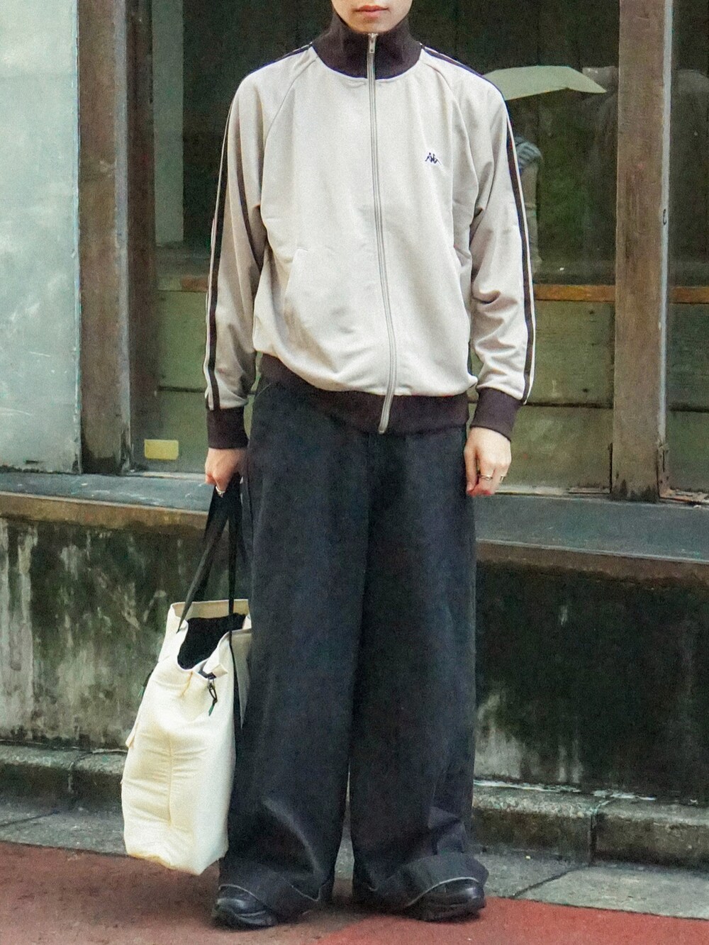 ベージュ系のジャージ、ブラック系のデニムパンツ、ホワイト系のバッグを着用したメンズの秋コーディネートの5枚目の写真