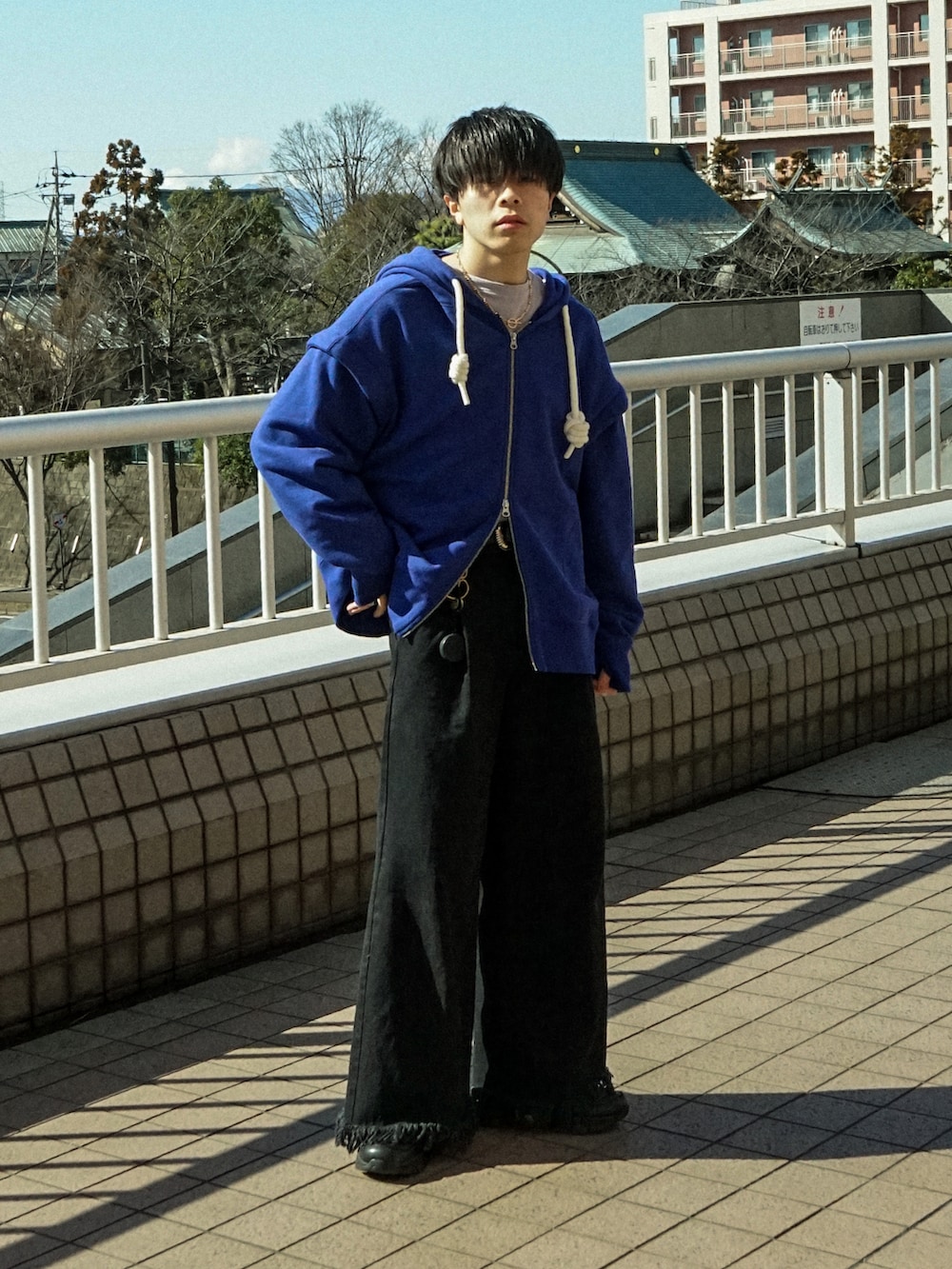 ブルー系のパーカー、ブラック系のデニムパンツ、ブラック系のスニーカーを着用したメンズの春コーディネートの2枚目の写真