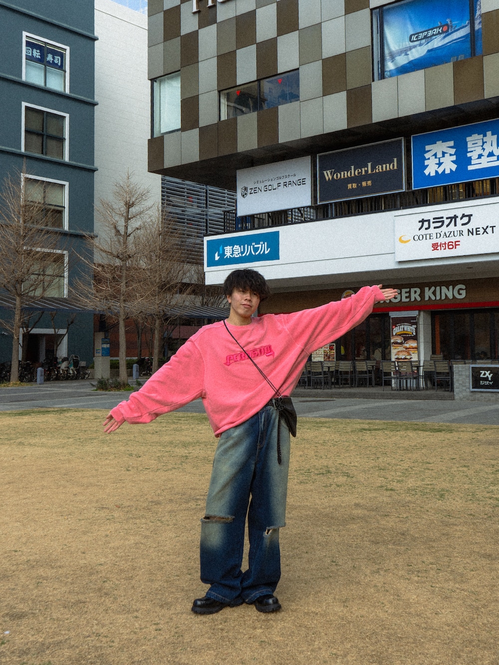 ピンク系のスウェット、ブルー系のデニムパンツ、ブラック系のショルダーバッグを着用したメンズの冬コーディネートの3枚目の写真