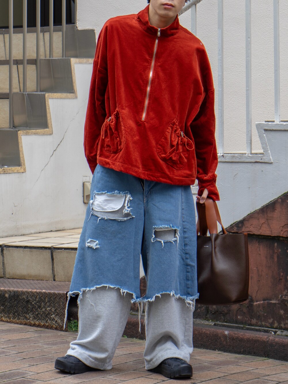 オレンジ系のブルゾン、グレー系のスウェットパンツ、ブラウン系のハンドバッグを着用したメンズの秋コーディネートの5枚目の写真