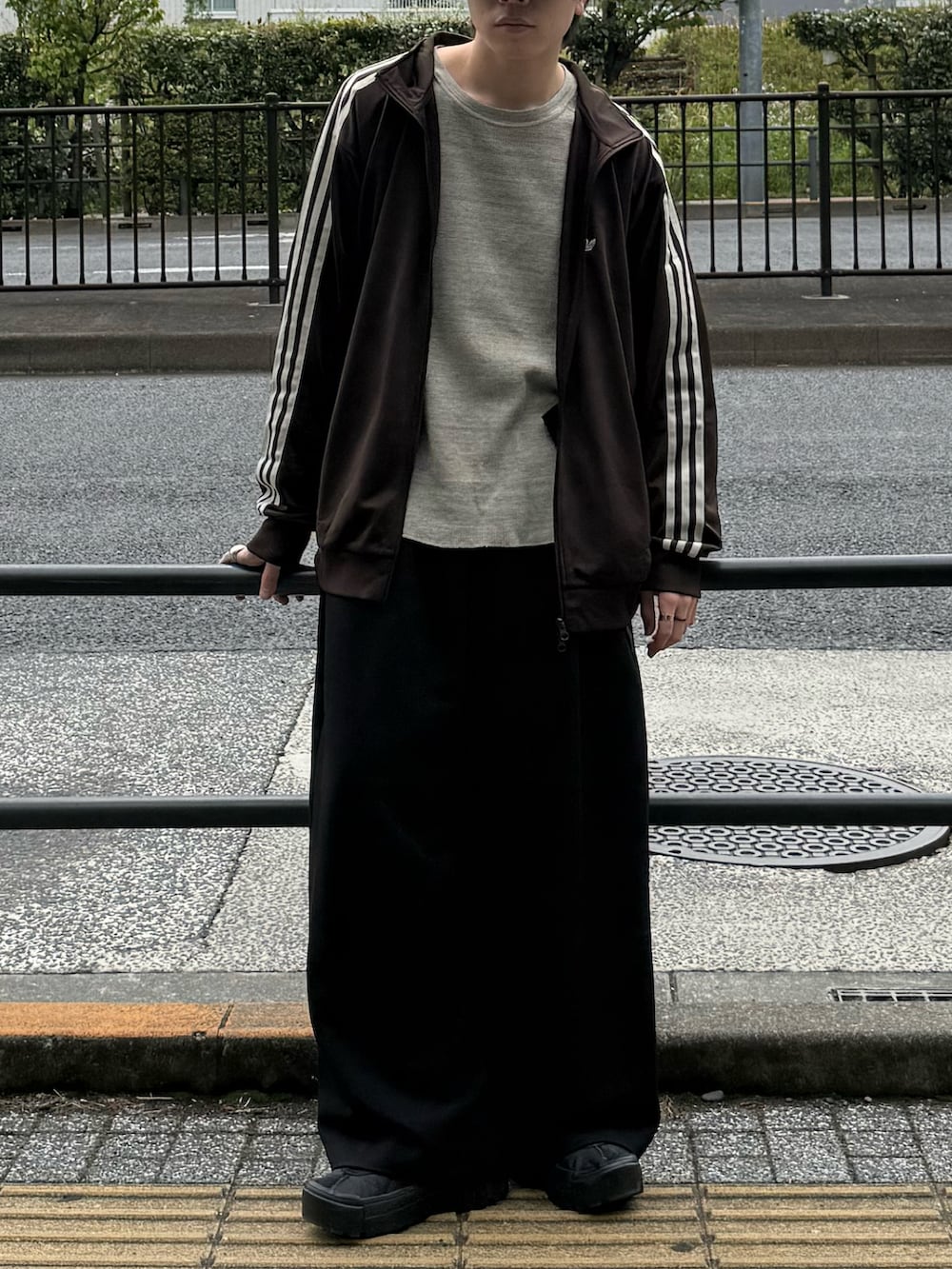 ブラウン系のジャージ、グレー系のTシャツ/カットソー、ブラック系のスラックスを着用したメンズの春コーディネートの4枚目の写真