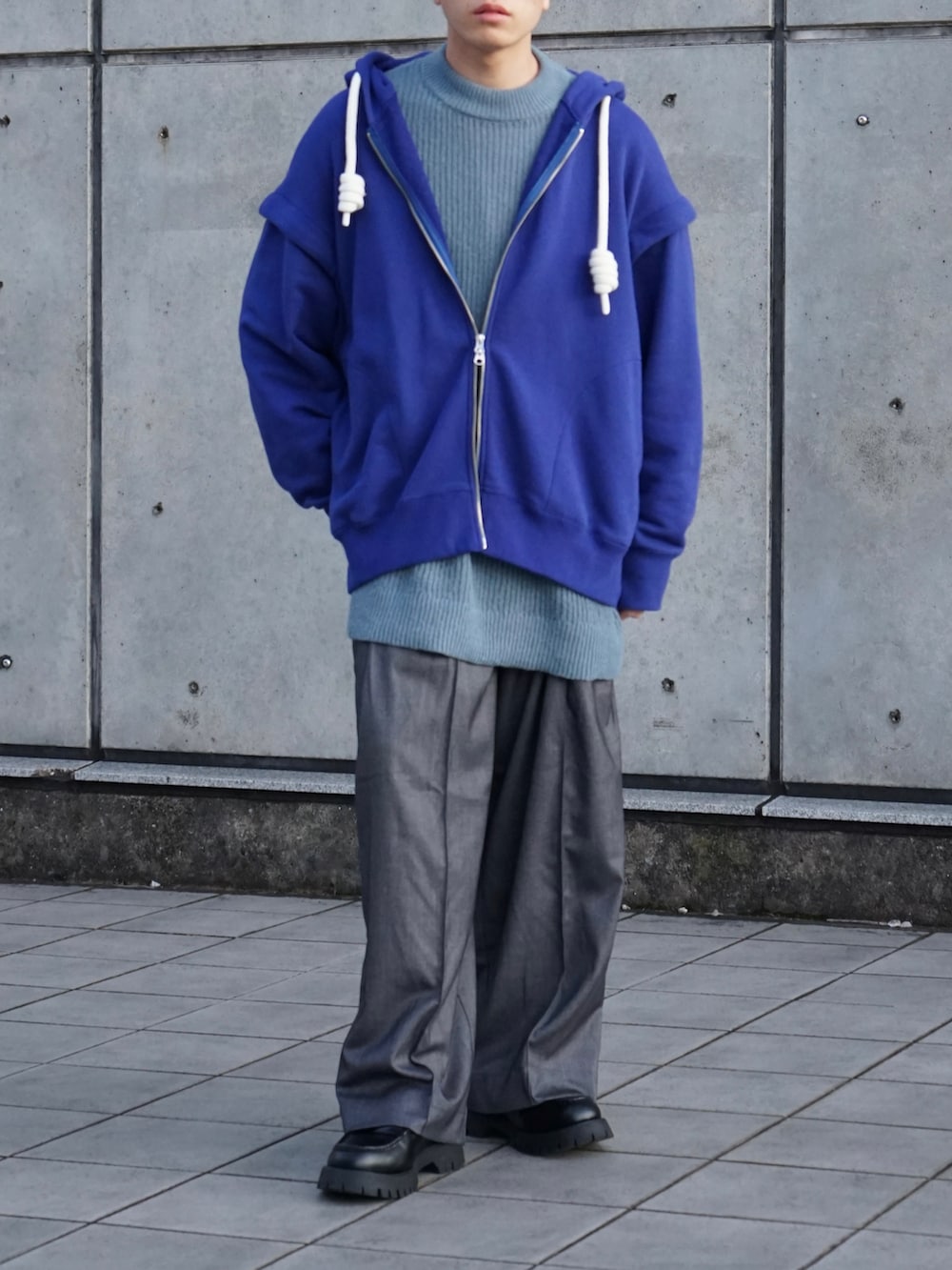ブルー系のパーカー、ブルー系のニット/セーター、グレー系のスラックスを着用したメンズの秋コーディネートの4枚目の写真