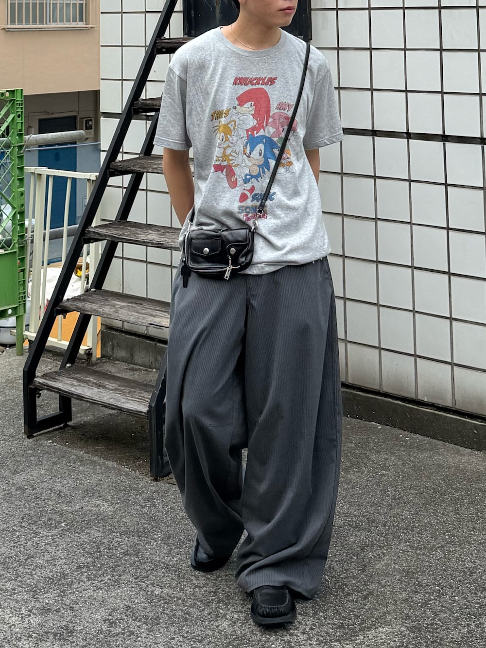 グレー系のTシャツ/カットソー、グレー系のスラックス、ブラック系のローファーを着用したメンズの夏コーディネートの4枚目の写真