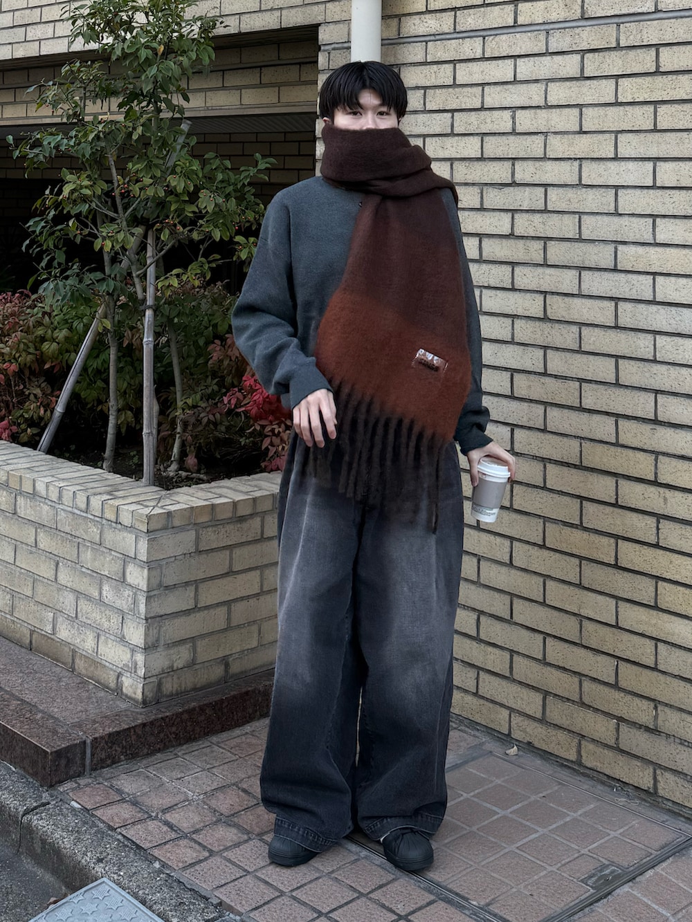 グレー系のニット/セーター、ブラック系のデニムパンツ、ブラック系のスニーカーを着用したメンズの冬コーディネートの2枚目の写真