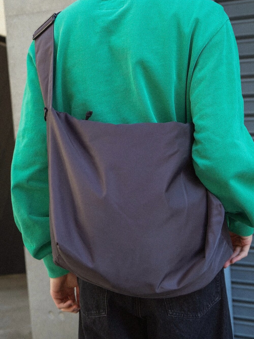 グリーン系のスウェット、ブラック系のデニムパンツ、グレー系のショルダーバッグを着用したメンズの冬コーディネートの4枚目の写真