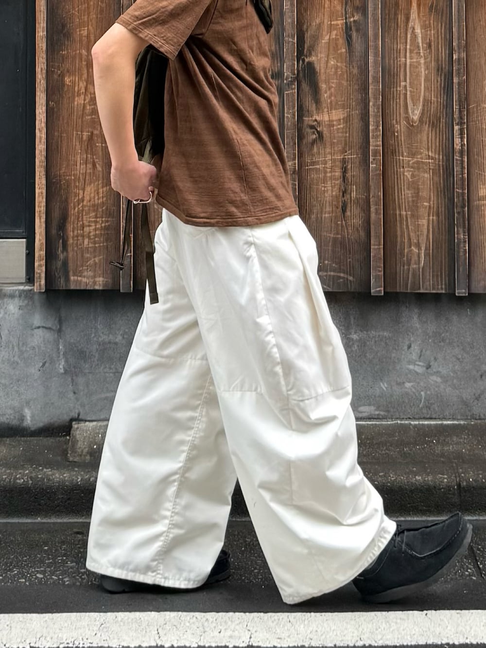ブラウン系のTシャツ/カットソー、グリーン系のバックパック/リュック、ホワイト系のその他パンツを着用したメンズの秋コーディネートの3枚目の写真