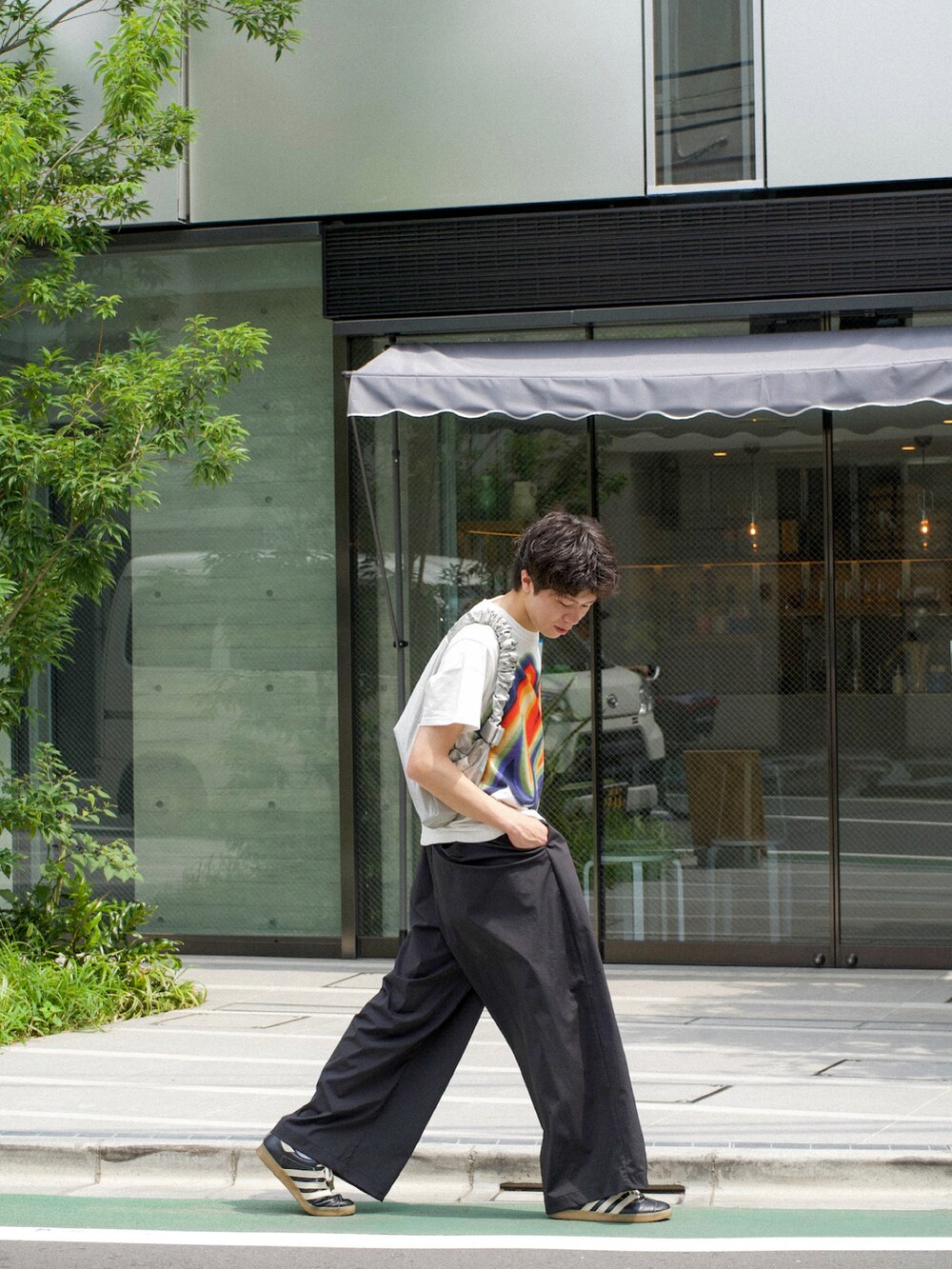 ホワイト系のTシャツ/カットソー、ブラック系のスラックス、ブラック系のスニーカーを着用したメンズの夏コーディネートの3枚目の写真