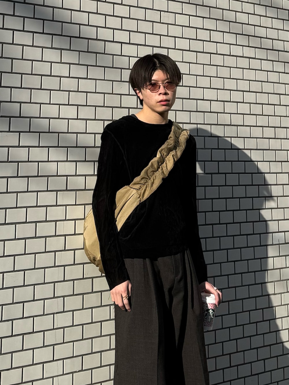 ブラック系のTシャツ/カットソー、ベージュ系のショルダーバッグ、ブラック系のブーツを着用したメンズの春コーディネートの2枚目の写真