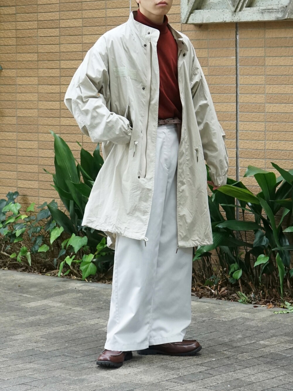 ベージュ系のモッズコート、レッド系のTシャツ/カットソー、ホワイト系のチノパンツを着用したメンズの秋コーディネートの5枚目の写真