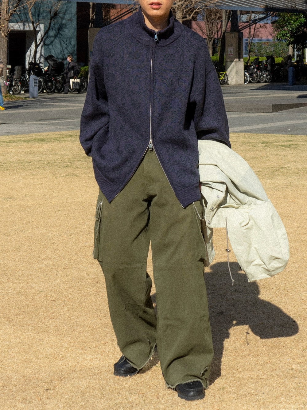 パープル系のニット/セーター、ベージュ系のマウンテンパーカー、グリーン系のカーゴパンツを着用したメンズの冬コーディネートの4枚目の写真