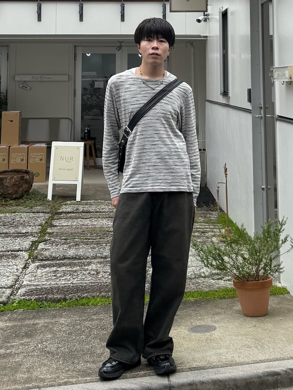 グレー系のTシャツ/カットソー、ブラウン系のデニムパンツ、ブラック系のショルダーバッグを着用したメンズの秋コーディネートの2枚目の写真