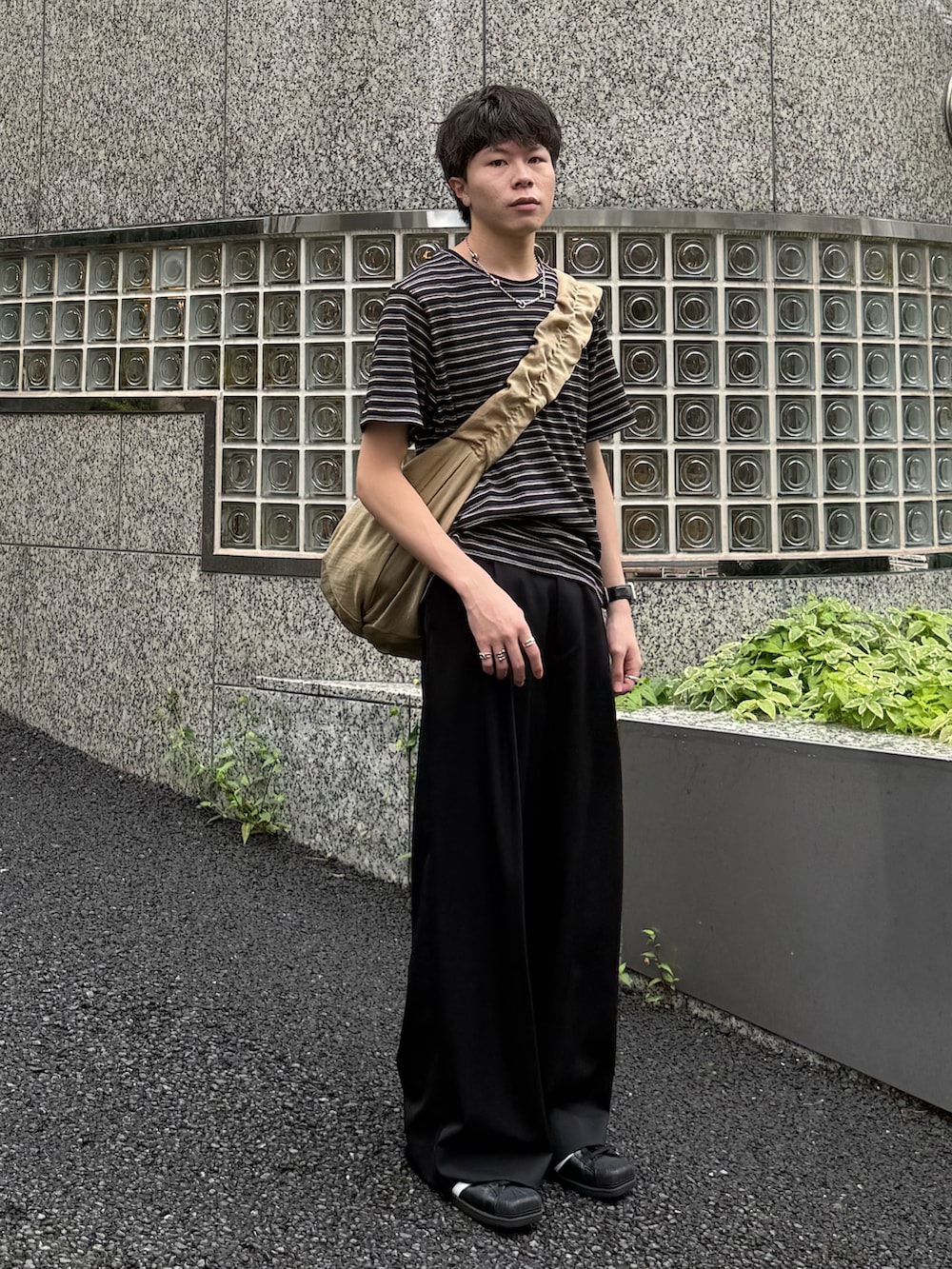 ブラック系のTシャツ/カットソー、ブラック系のスラックス、ベージュ系のショルダーバッグを着用したメンズの夏コーディネートの2枚目の写真