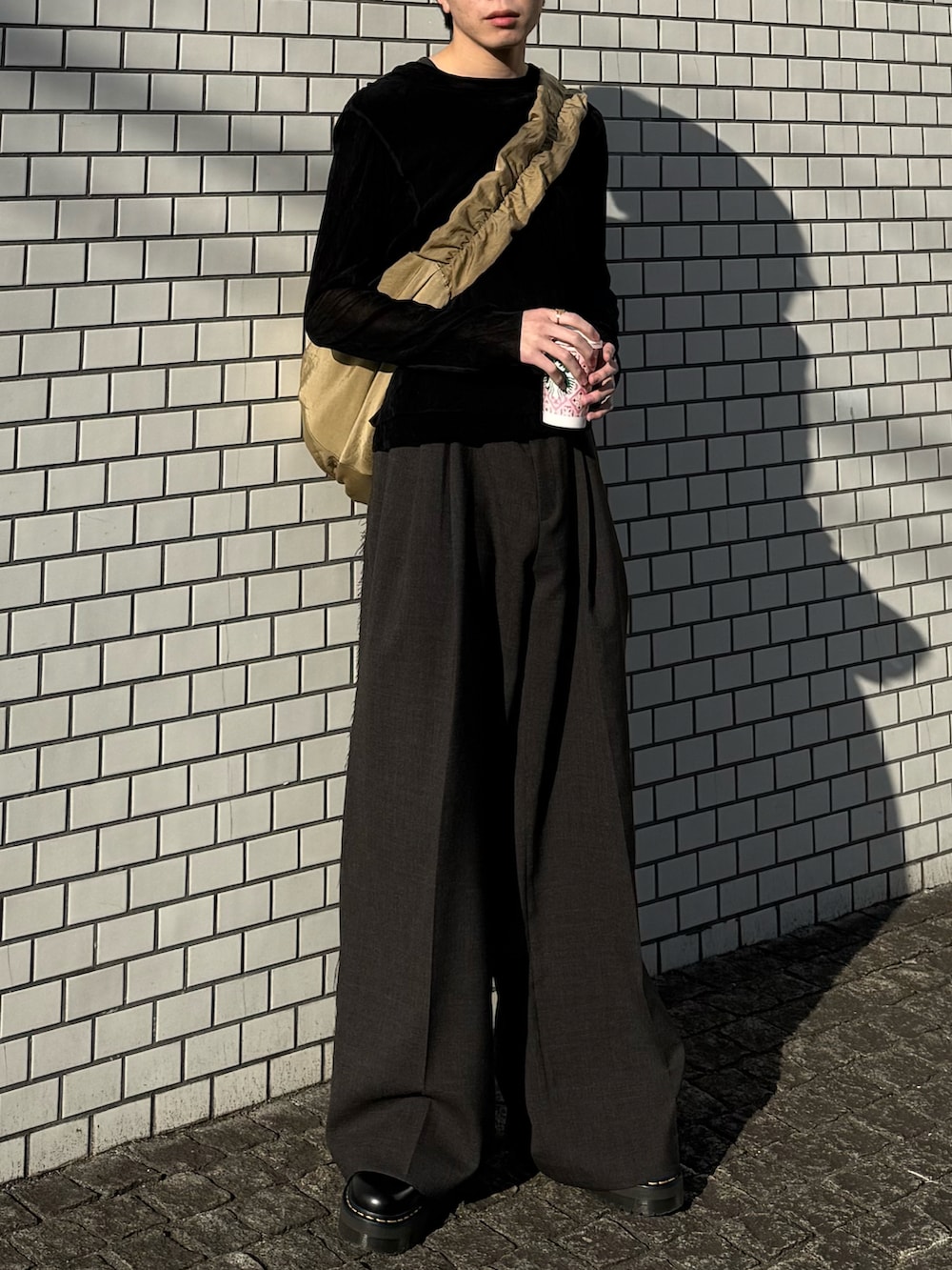 ブラック系のTシャツ/カットソー、ベージュ系のショルダーバッグ、ブラック系のブーツを着用したメンズの春コーディネートの4枚目の写真