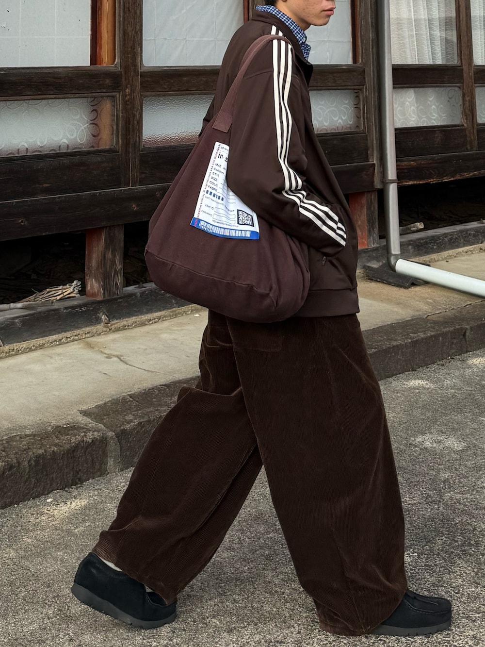 ブラウン系のジャージ、ブラウン系のトートバッグ、ブラック系のモカシン/デッキシューズを着用したメンズの秋コーディネートの2枚目の写真
