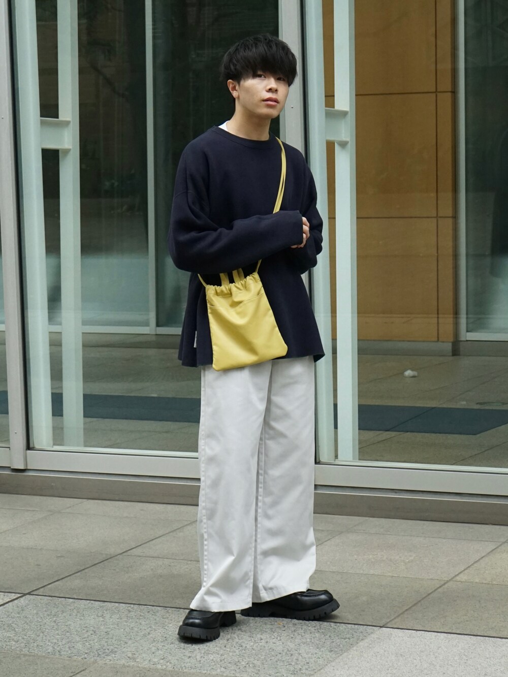 グリーン系のニット/セーター、ホワイト系のチノパンツ、イエロー系のショルダーバッグを着用したメンズの秋コーディネートの3枚目の写真