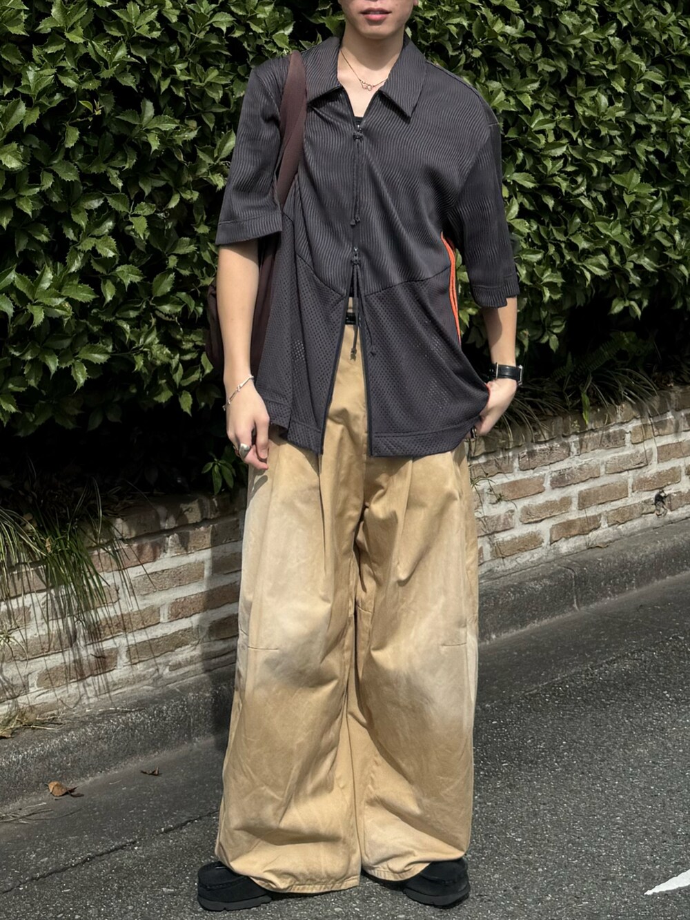 ベージュ系のチノパンツ、ブラウン系のトートバッグ、グレー系のトップスを着用したメンズの夏コーディネートの5枚目の写真