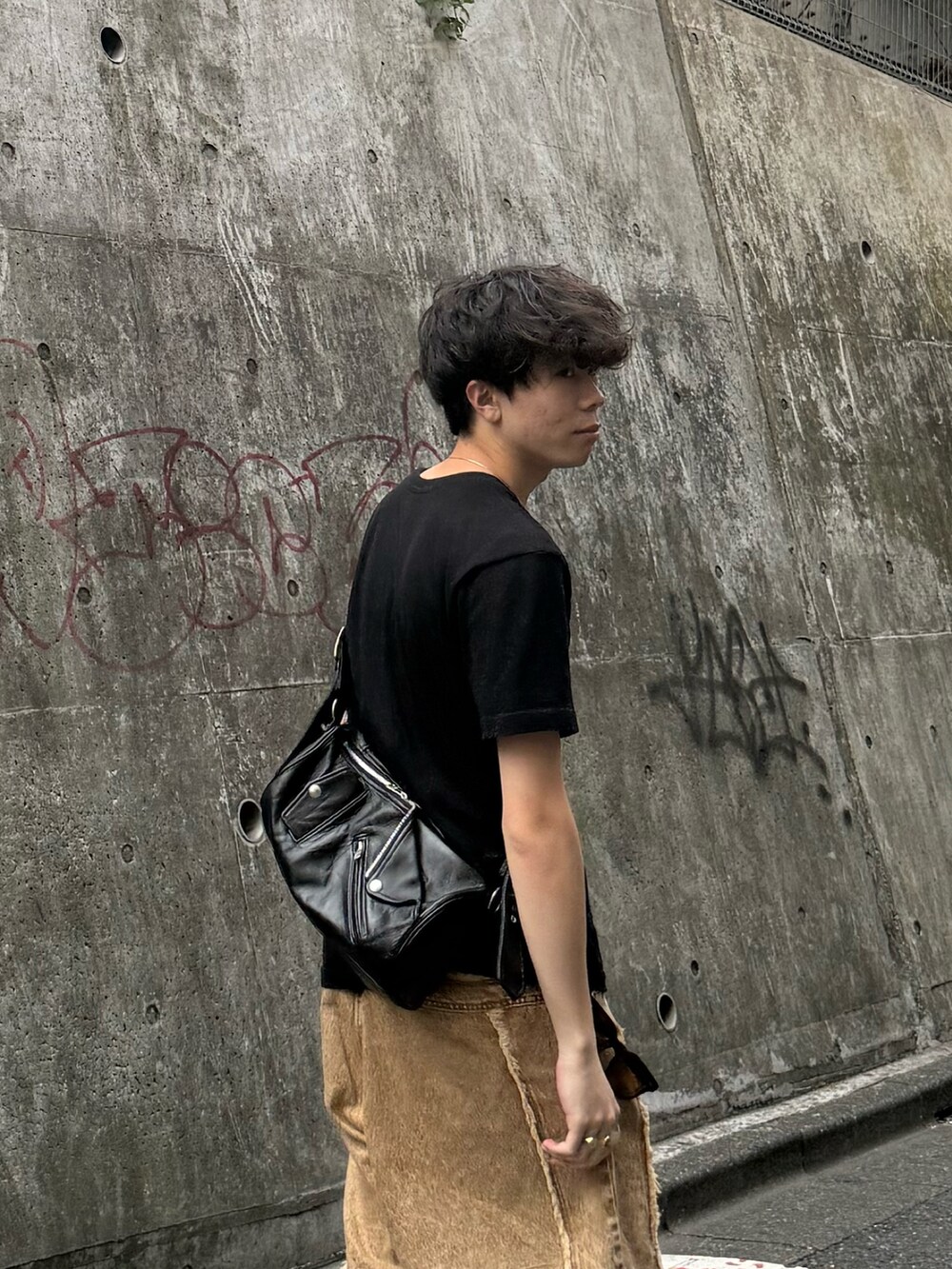 ブラック系のTシャツ/カットソー、ベージュ系のその他パンツ、ブラック系のショルダーバッグを着用したメンズの夏コーディネートの3枚目の写真