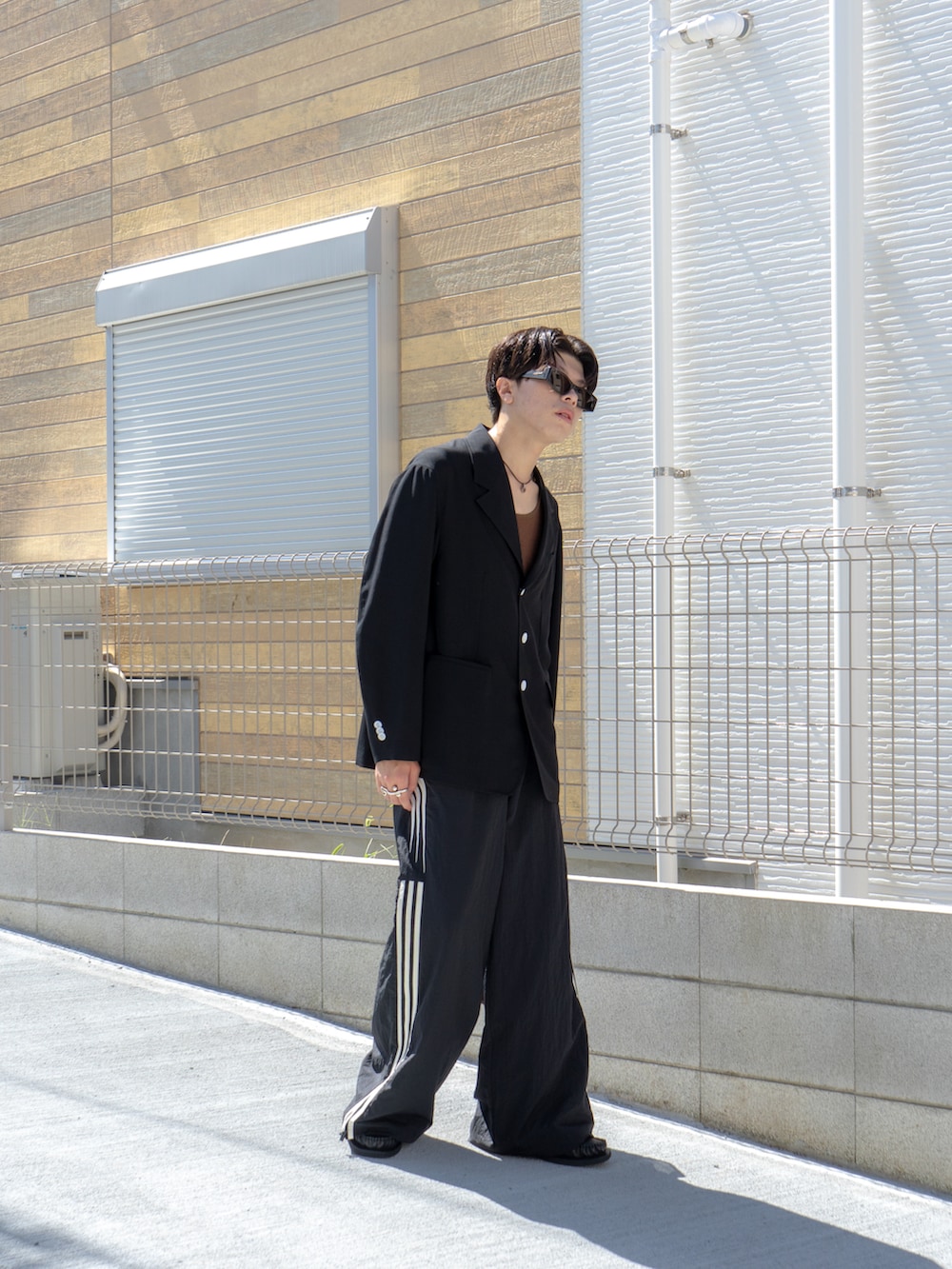 ブラック系のテーラードジャケット、ブラウン系のタンクトップ、ブラック系のスウェットパンツを着用したメンズの秋コーディネートの3枚目の写真