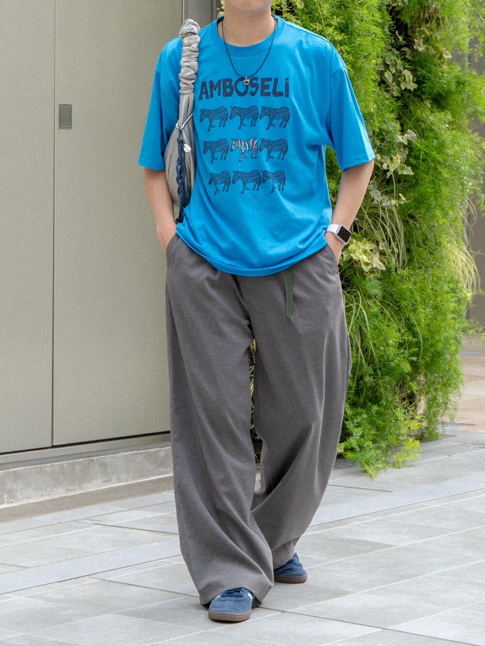 ブルー系のTシャツ/カットソー、グレー系のスラックス、ブルー系のスニーカーを着用したメンズの夏コーディネートの5枚目の写真