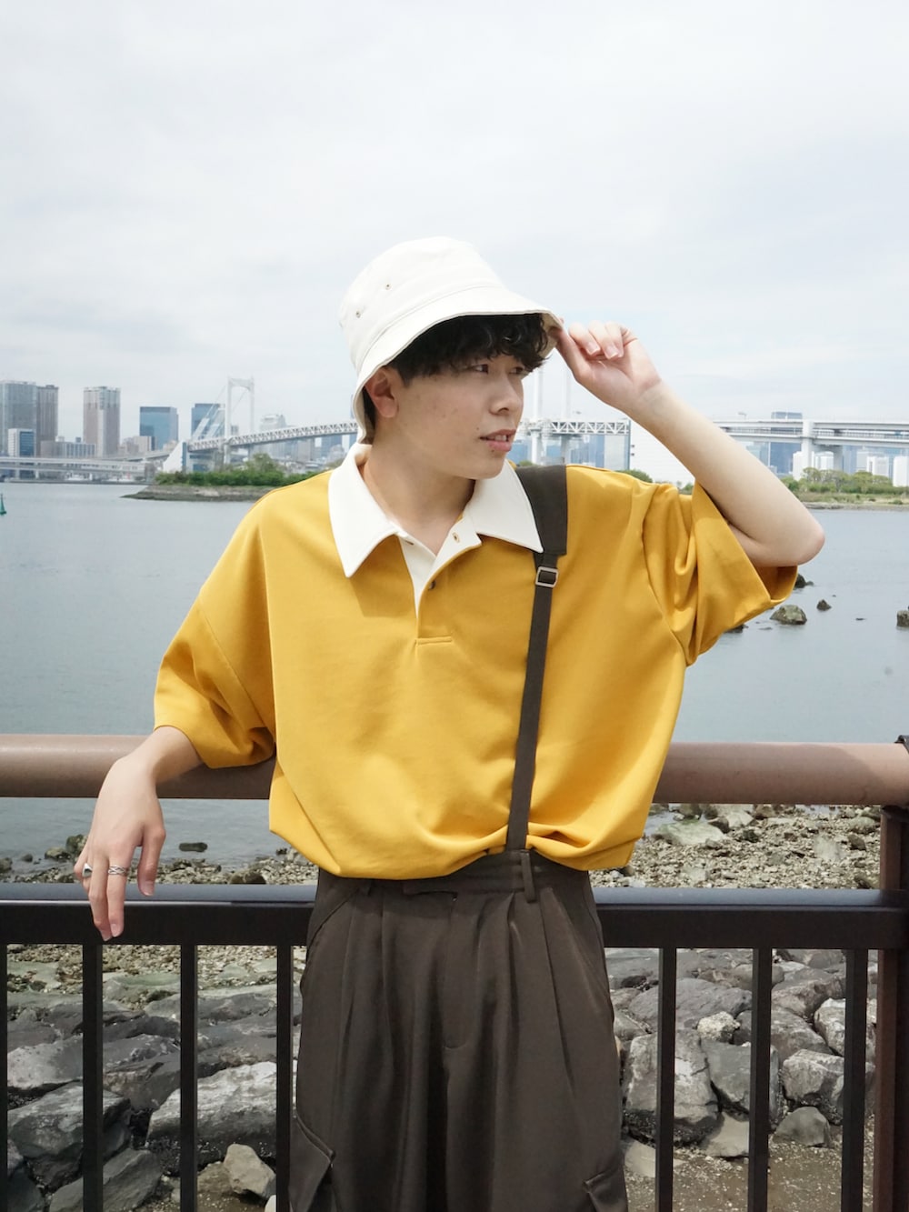 イエロー系のポロシャツ、グリーン系のサロペット/オーバーオール、ブラウン系のサンダルを着用したメンズの春コーディネートの3枚目の写真