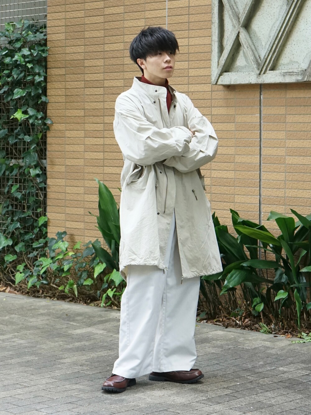 ベージュ系のモッズコート、レッド系のTシャツ/カットソー、ホワイト系のチノパンツを着用したメンズの秋コーディネートの3枚目の写真