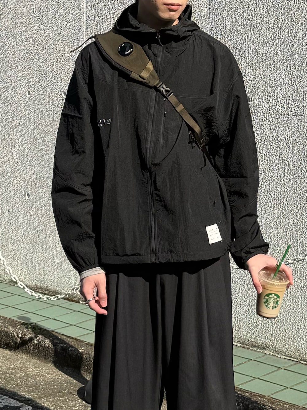 ブラック系のその他アウター、グリーン系のバックパック/リュック、グレー系のスラックスを着用したメンズの春コーディネートの3枚目の写真