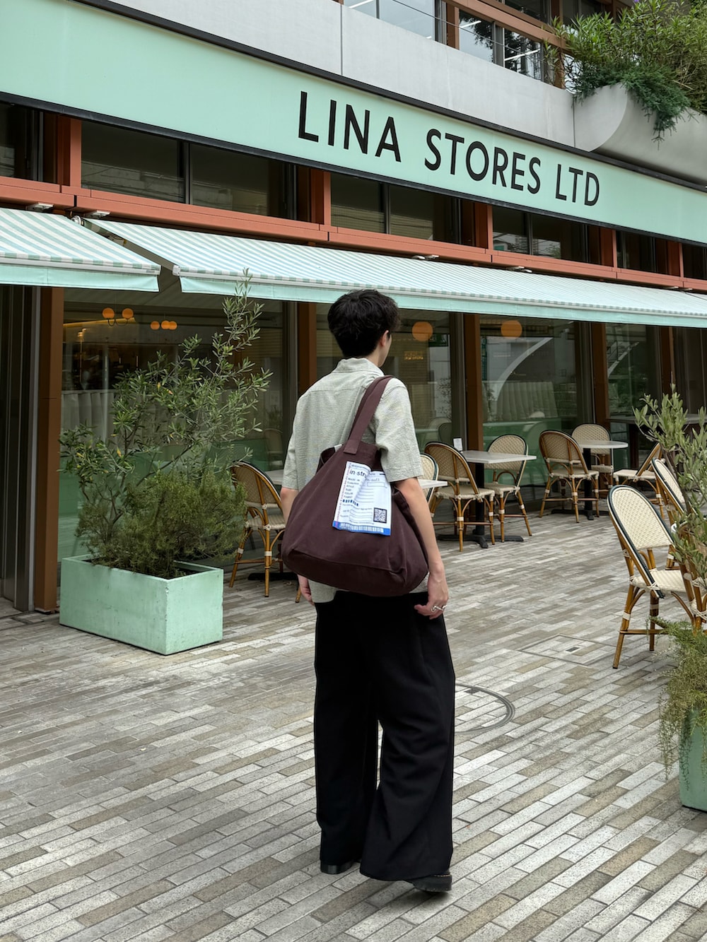 グリーン系のシャツ/ブラウス、ブラック系のスラックス、ブラウン系のトートバッグを着用したメンズの夏コーディネートの3枚目の写真