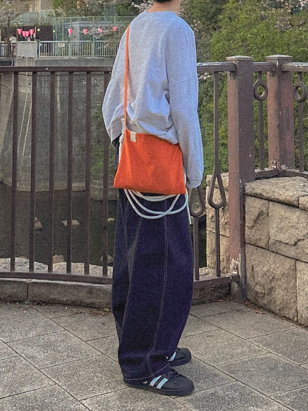 グレー系のスウェット、ブルー系のデニムパンツ、オレンジ系のショルダーバッグを着用したメンズの春コーディネートの5枚目の写真