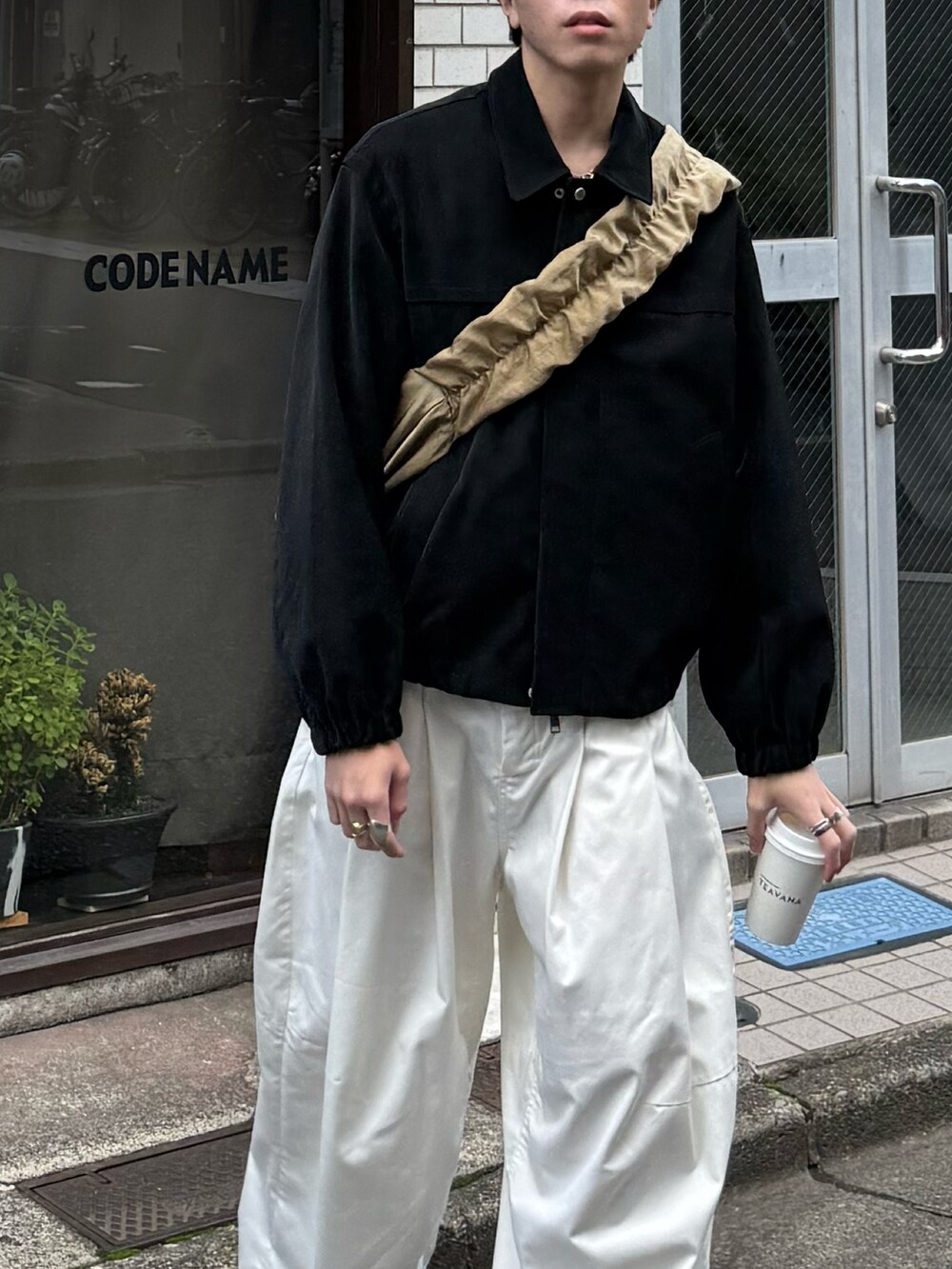 ブラック系のブルゾン、ホワイト系のその他パンツ、ベージュ系のショルダーバッグを着用したメンズの秋コーディネートの3枚目の写真