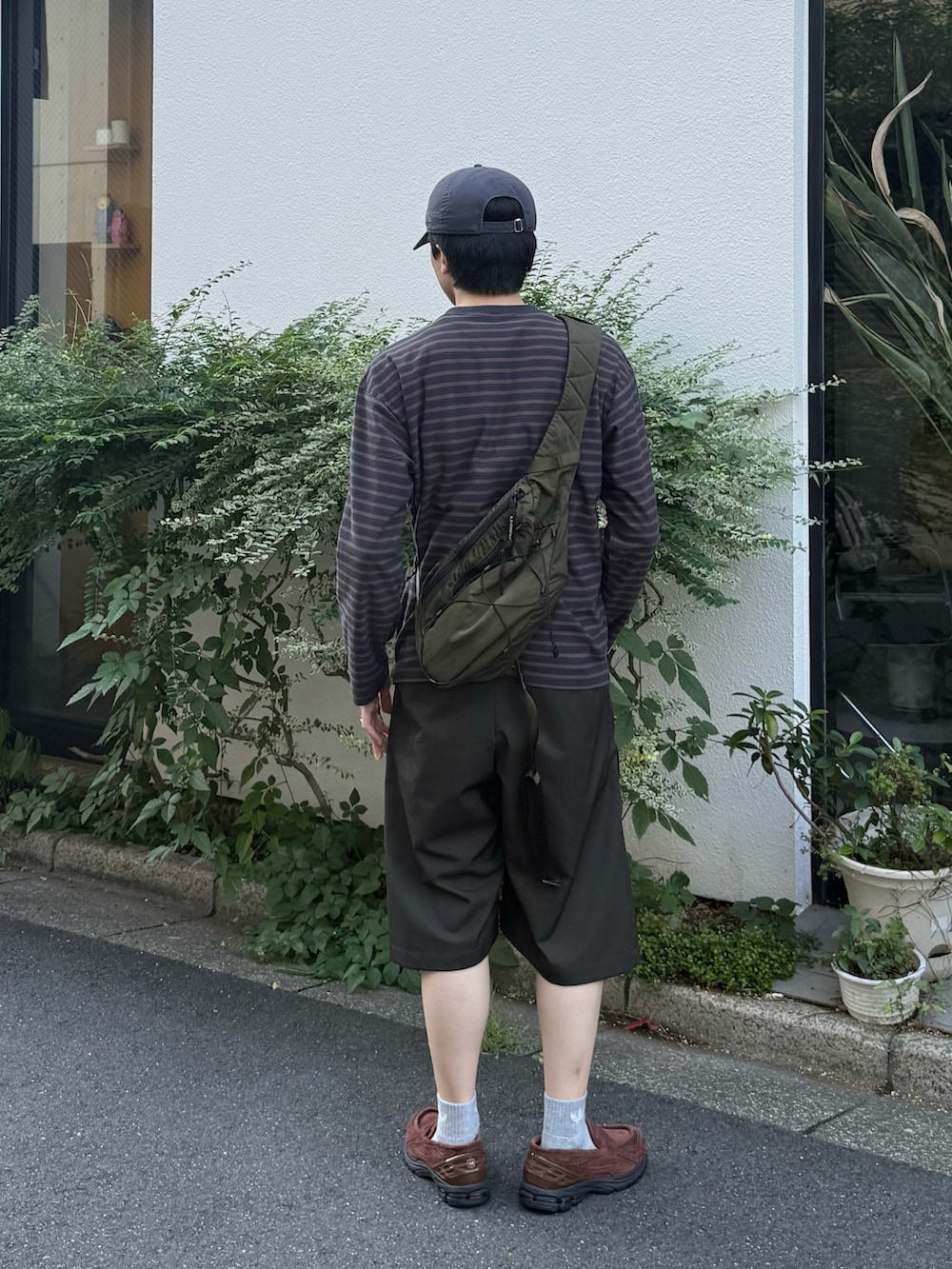 グレー系のTシャツ/カットソー、グリーン系のバックパック/リュック、グリーン系のスラックスを着用したメンズの秋コーディネートの2枚目の写真
