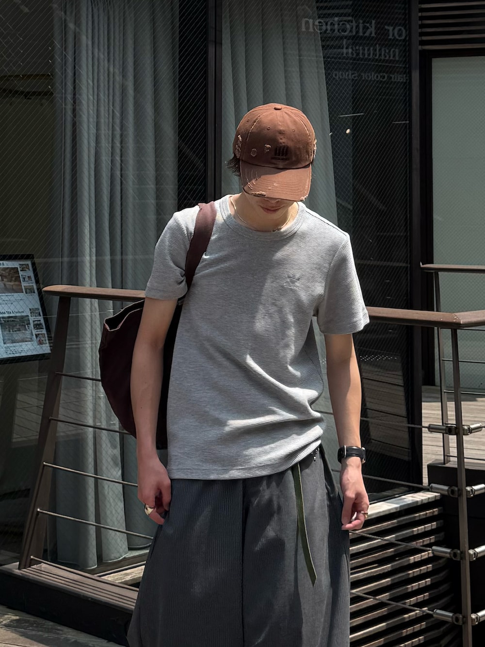 グレー系のTシャツ/カットソー、グレー系のスラックス、ブラウン系のトートバッグを着用したメンズの夏コーディネートの3枚目の写真