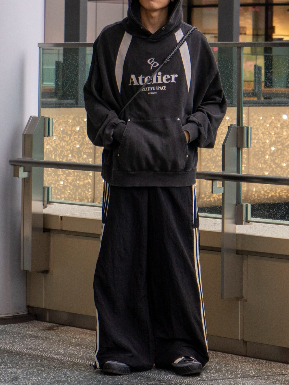 ブラック系のパーカー、ブラック系のスウェットパンツ、ブラウン系のショルダーバッグを着用したメンズの秋コーディネートの5枚目の写真