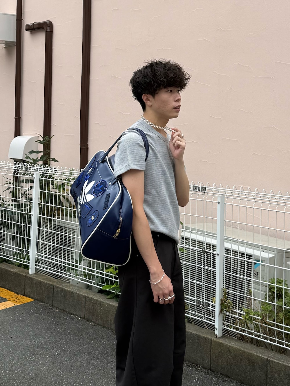 グレー系のTシャツ/カットソー、グレー系のスラックス、ブルー系のボストンバッグを着用したメンズの夏コーディネートの3枚目の写真