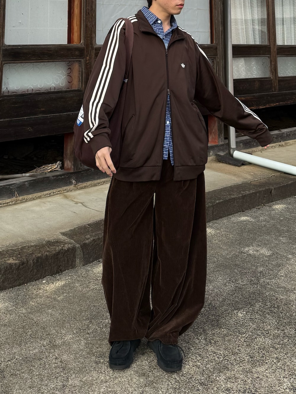 ブラウン系のジャージ、ブラウン系のトートバッグ、ブラック系のモカシン/デッキシューズを着用したメンズの秋コーディネートの4枚目の写真