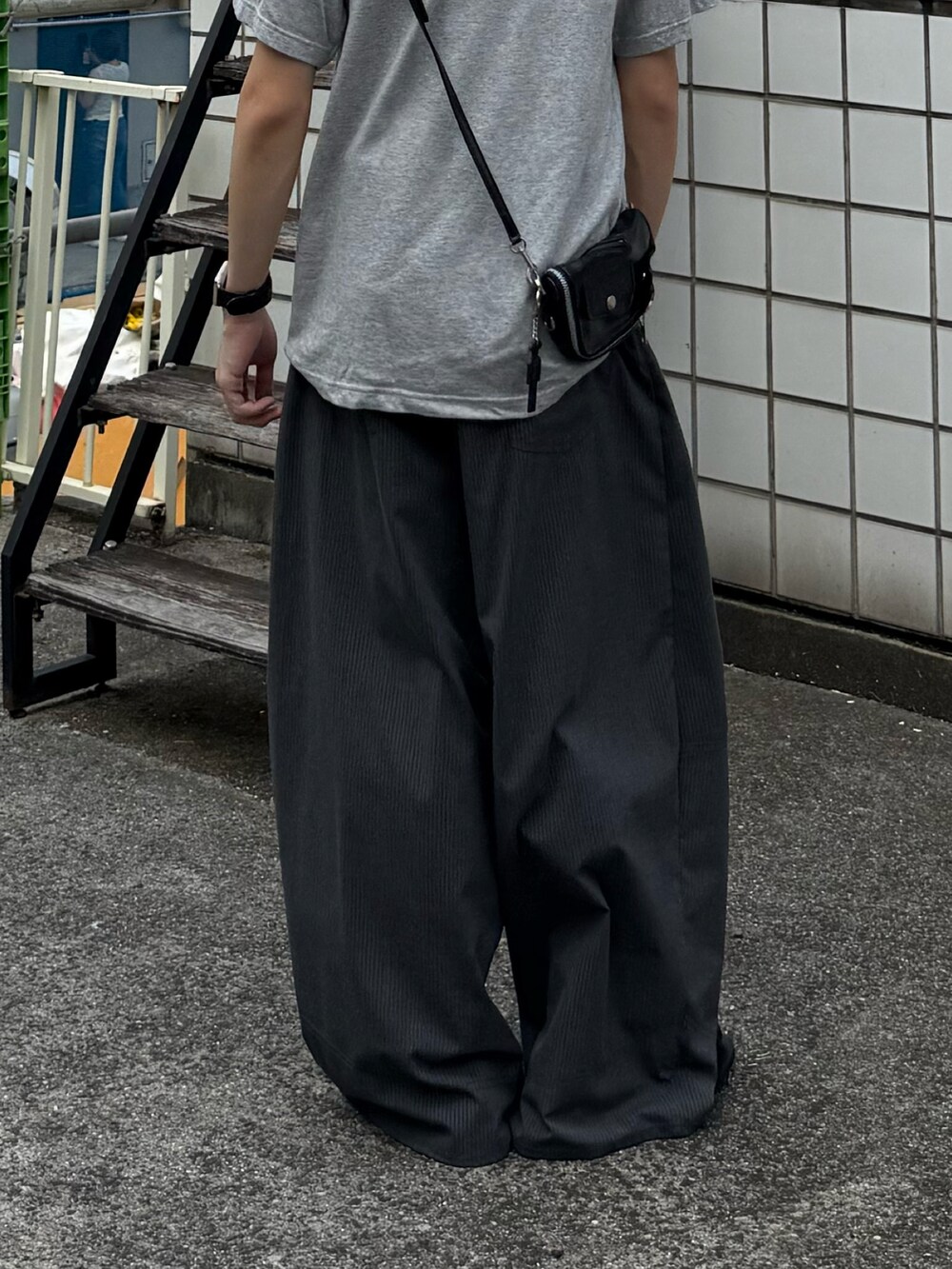グレー系のTシャツ/カットソー、グレー系のスラックス、ブラック系のローファーを着用したメンズの夏コーディネートの3枚目の写真