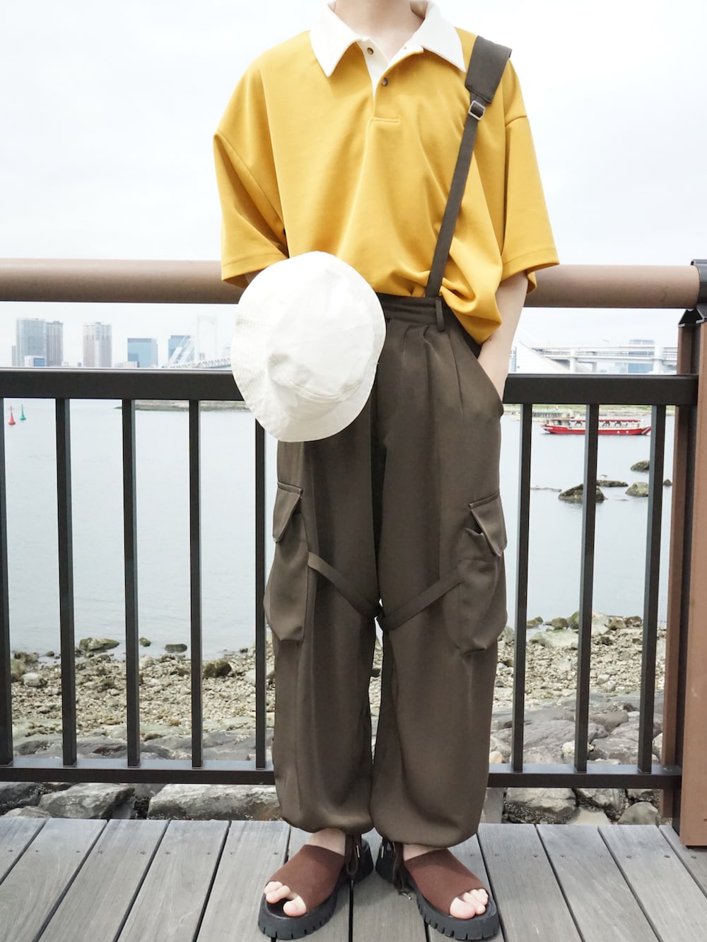 イエロー系のポロシャツ、グリーン系のサロペット/オーバーオール、ブラウン系のサンダルを着用したメンズの春コーディネートの4枚目の写真