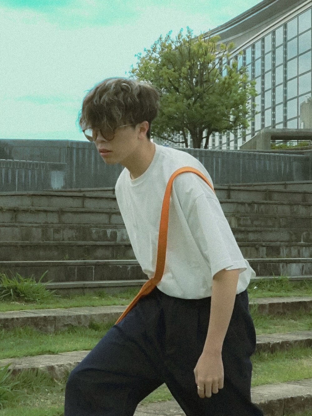 ホワイト系のTシャツ/カットソー、ブルー系のデニムパンツ、オレンジ系のショルダーバッグを着用したメンズの春コーディネートの4枚目の写真