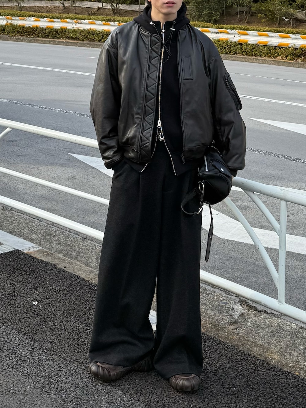 ブラウン系のMA-1、ブラック系のパーカー、グレー系のスラックスを着用したメンズの冬コーディネートの4枚目の写真