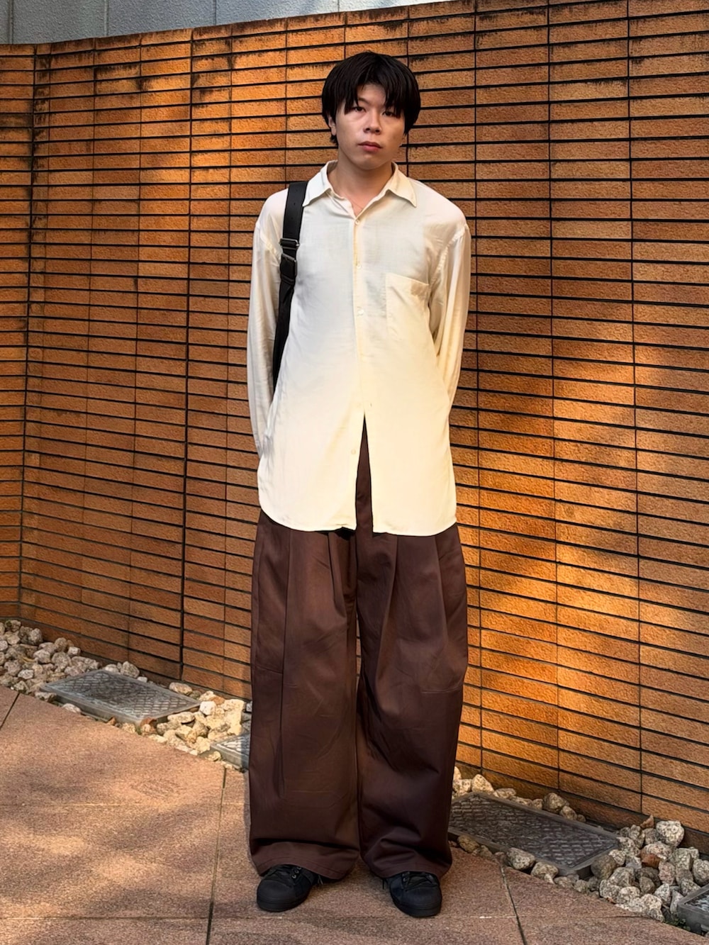 ブラウン系のショルダーバッグ、ブラウン系のその他パンツ、ブラック系のスニーカーを着用したメンズの秋コーディネートの2枚目の写真