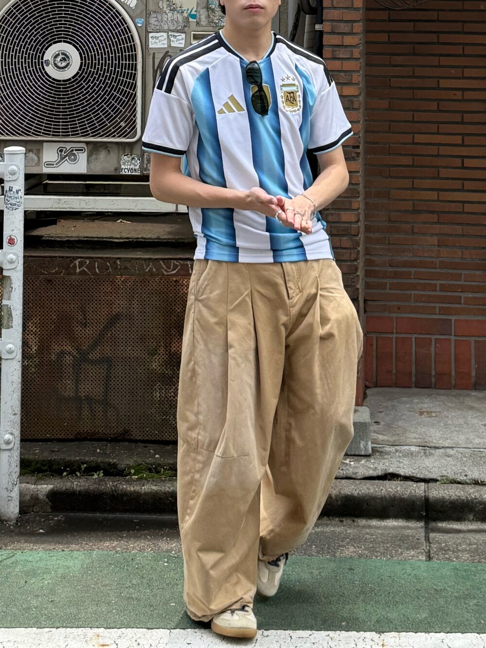 ホワイト系のTシャツ/カットソー、ベージュ系のチノパンツ、ホワイト系のスニーカーを着用したメンズの夏コーディネートの3枚目の写真