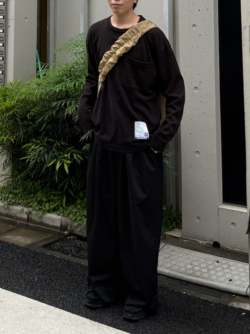 ブラック系のTシャツ/カットソー、ブラック系のその他パンツ、ベージュ系のショルダーバッグを着用したメンズの春コーディネートの3枚目の写真