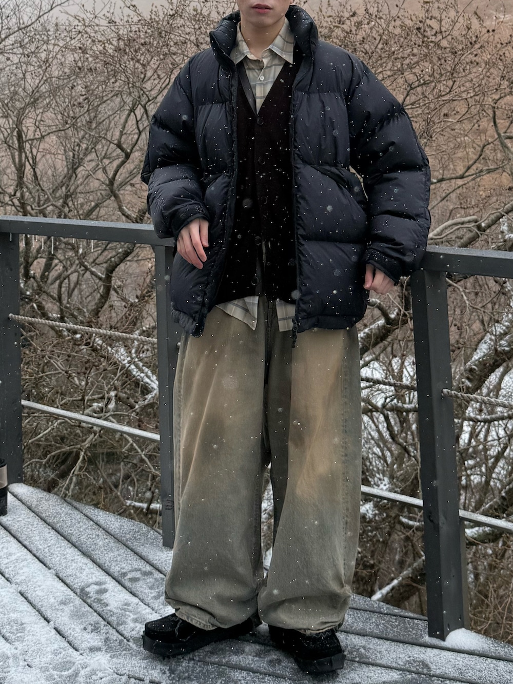 ブラック系のダウンジャケット/コート、ブラウン系のカーディガン/ボレロ、ベージュ系のシャツ/ブラウスを着用したメンズの冬コーディネートの4枚目の写真