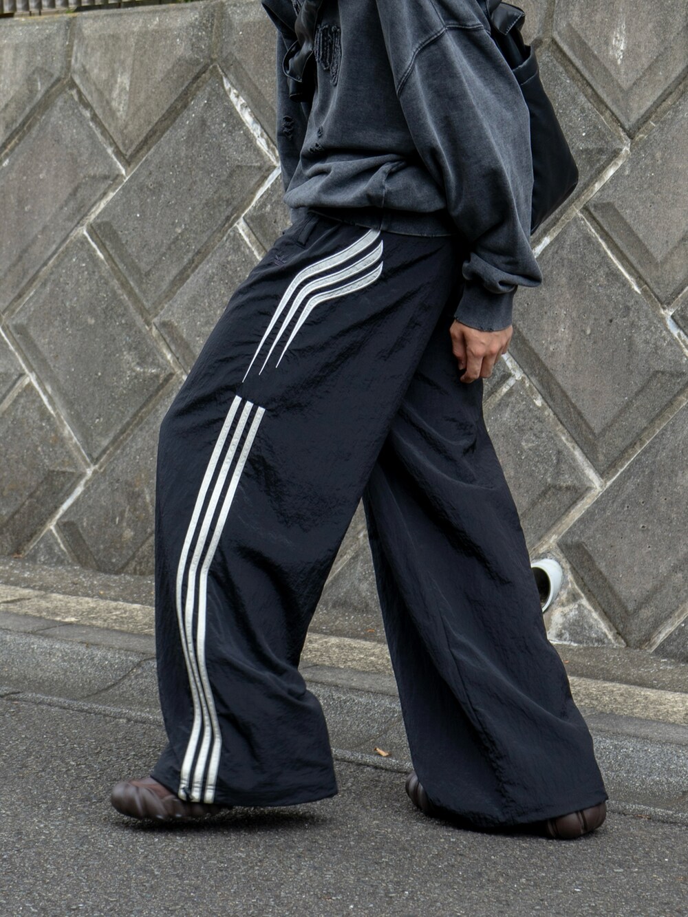 グレー系のスウェット、ブラック系のショルダーバッグ、ブラック系のスウェットパンツを着用したメンズの秋コーディネートの4枚目の写真