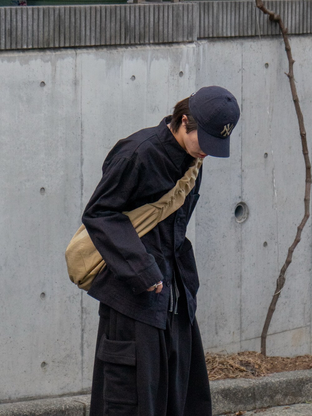 ブラック系のカバーオール、ブラック系のスウェットパンツ、ベージュ系のショルダーバッグを着用したメンズの冬コーディネートの3枚目の写真