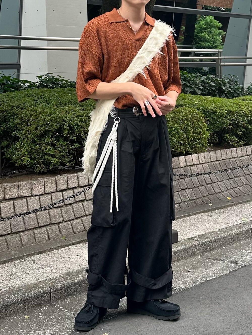 ブラウン系のポロシャツ、ブラック系のカーゴパンツ、ホワイト系のショルダーバッグを着用したメンズの夏コーディネートの5枚目の写真