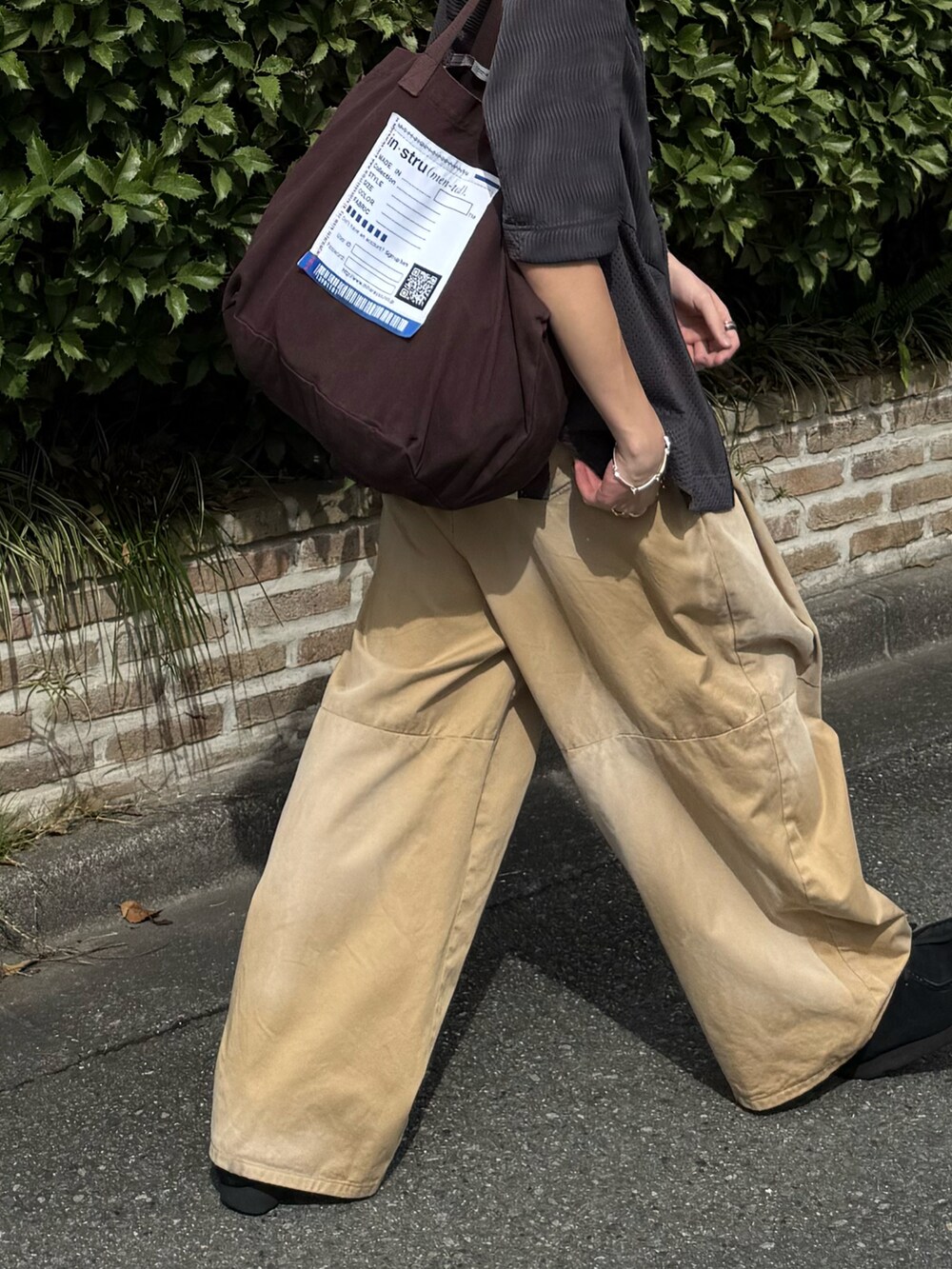 ベージュ系のチノパンツ、ブラウン系のトートバッグ、グレー系のトップスを着用したメンズの夏コーディネートの4枚目の写真