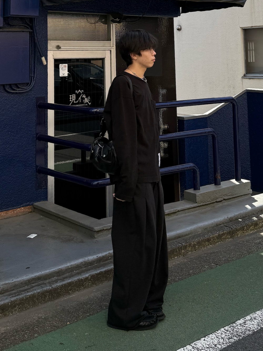 ブラック系のTシャツ/カットソー、ブラック系のショルダーバッグ、ブラック系のスウェットパンツを着用したメンズの秋コーディネートの2枚目の写真
