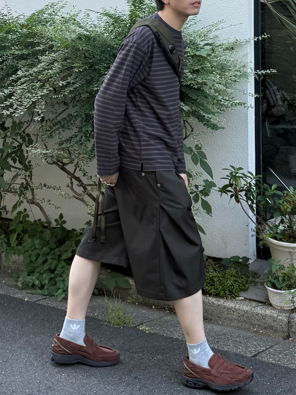 グレー系のTシャツ/カットソー、グリーン系のバックパック/リュック、グリーン系のスラックスを着用したメンズの秋コーディネートの4枚目の写真